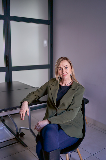 blonde woman with long hair in a green jacket and jeans in the office