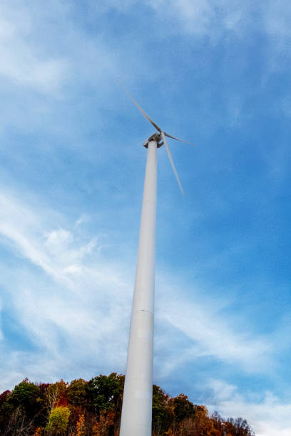 A below perspective on a single wind turbine with a blue and cloud swept background.