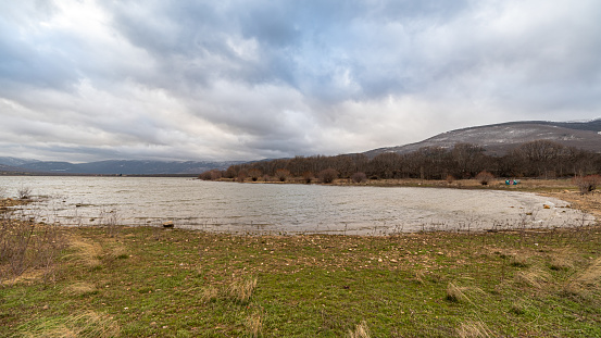 Lozoya del Valle reservoir with cloudy sky and Sierra mountains in the background in Madrid, Spain