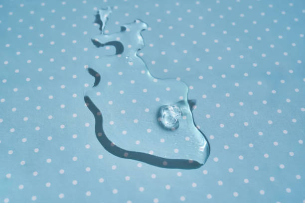 A drop of water or cosmetic serum on a blue polka dot background. High quality photo