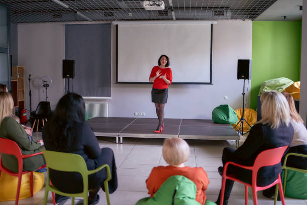istock woman giving emotional speech on stage, performance hall in office 2098468347