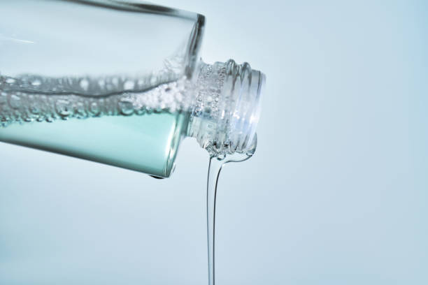 istock Cosmetic bottle from which serum is pouring on a blue background. 2098469919
