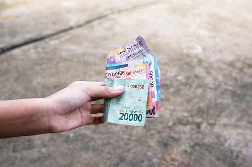 women show Indonesian money as a legitimate payment instrument with a blur background