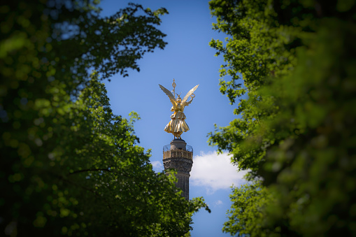 Berlin, Germany – March 05, 2014: The Angel statue seen behind green trees in Berlin, Germany