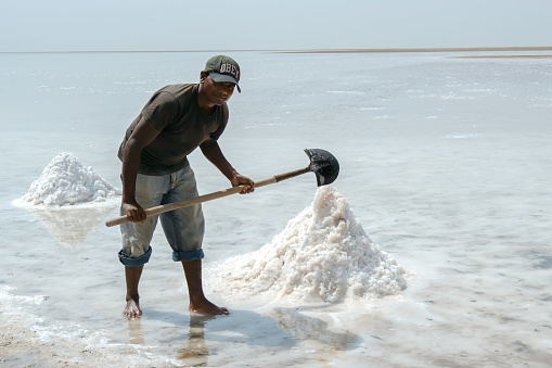 Mahut, Oman – September 11, 2012: A man collecting natural salt from a slat lake