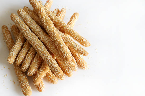 Long artisanal breadsticks with sesame seeds isolated on white background. Bakery products. Copy space. Overhead view.