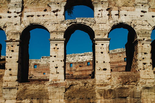 detail of the ancient perimeter walls upper corner of the Colosseum viewed from the outside with blue sky, Rome Italy