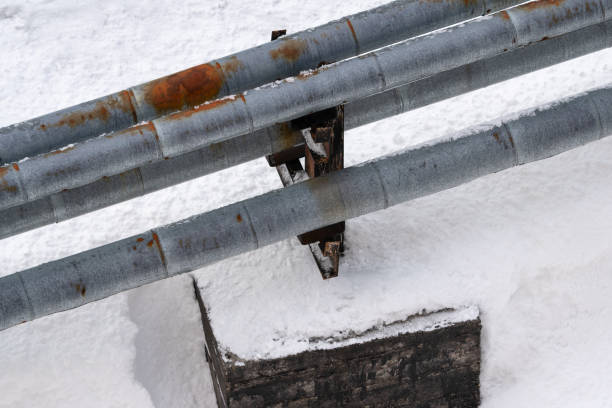 istock External city central heating pipes, with rusty thermal insulation jackets above snow after snowfall 2098530099