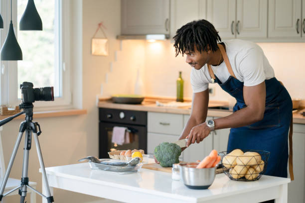 istock Cutting broccoli on a cutting board using a sharp knife, a male vlogger is demostrating a pescatarianism recipe 2098539685