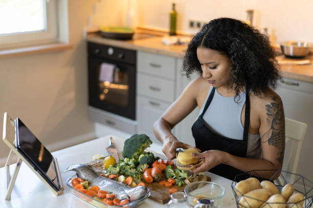 istock Learning from an online recipe a woman is preparing dinner 2098539700
