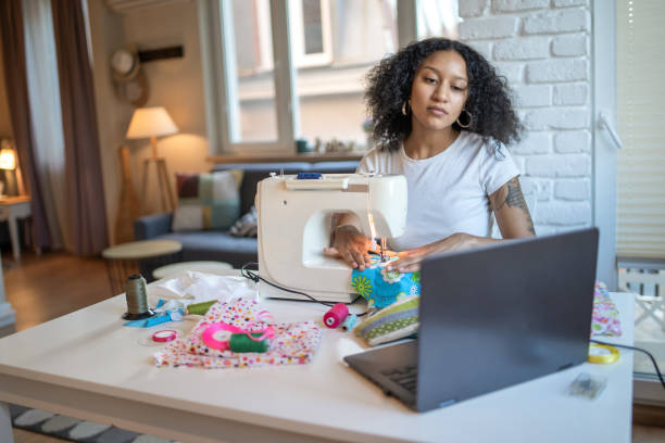 istock Woman watching online sewing video and using a sewing machine 2098544060