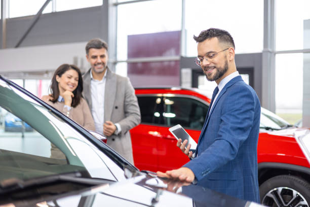 istock Salesman presenting car features to couple 2098564331