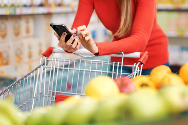 istock Woman using a smartphone at the supermarket 2098578368