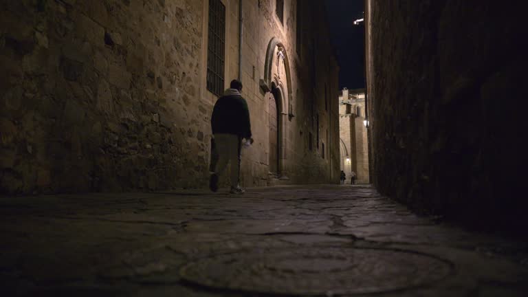 Man walking down dark alleyway in Caceres, Spain