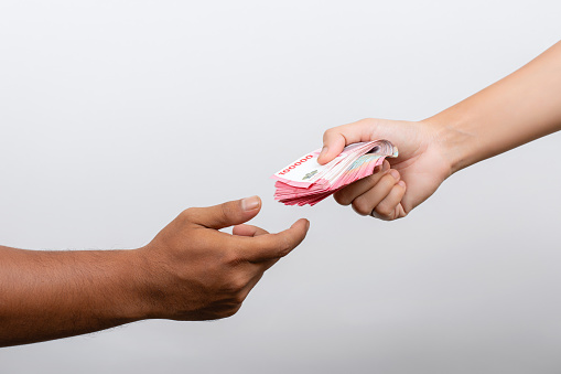 Closeup of hands giving rupiah money isolated on white background. Rupiah Indonesian money pay salaries concept.