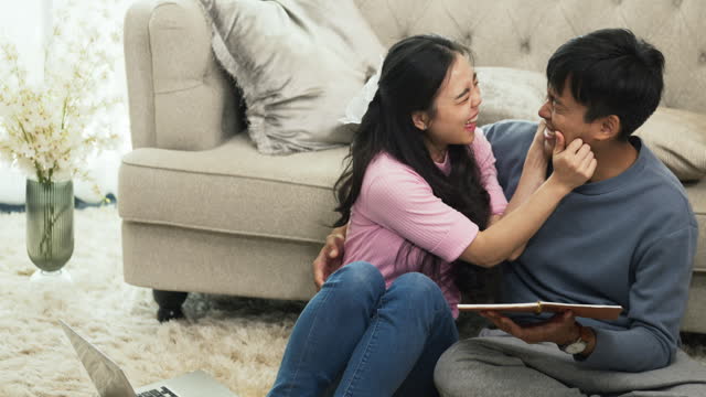 Attractive young couple reading interesting book and resting during weekend at living room.