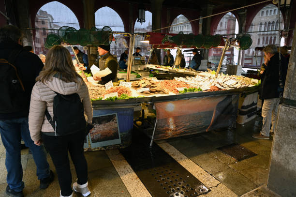 Venice, Italy, march 12, 2024 : Customers in front of a fish stall at the Rialto covered market in Venice