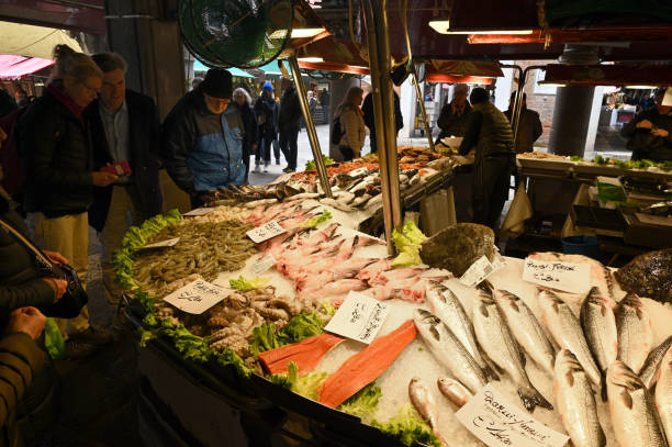 03/02/2025 Venice. Italy\nMan in admiral costume shopping in the famous market place near Rialto Bridge, during Venice Carnival 2025.