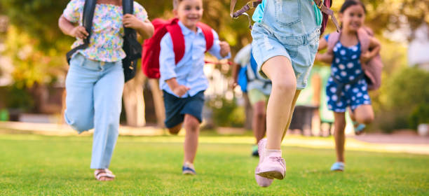 istock Close Up Of Primary Or Elementary School Students With Backpacks Running Outdoors At End Of Day 2098615409