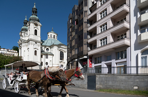 Karlovy Vary, Czech Republic -  June 3, 2023. Tourists enjoy a traditional horse-drawn carriage ride, showcasing the city's charming architecture and vibrant culture.