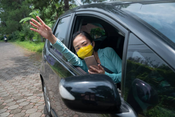 istock Asian female driver waving to her customer from inside her car. 2098633816