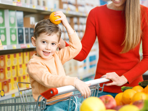 istock Cute boy holding a fresh orange at the supermarket 2098708209