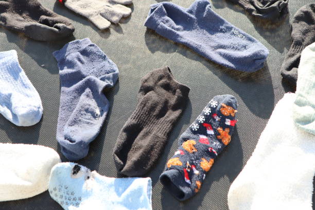 Female hand holds black men's socks on a white background. The concept of unpleasant foot odor and fungal diseases on the legs. Antiperspirants against foot odor, fumigation