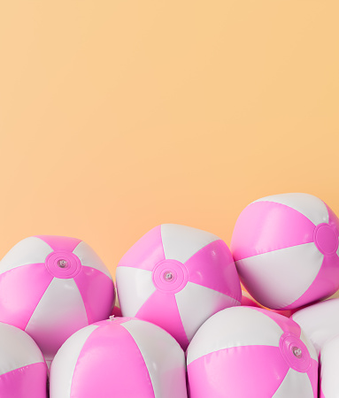 3D rendering of multiple pink and white beach balls stacked with an ample copyspace on a peach-colored background. Summer fun concept.
