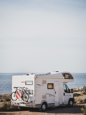 White over cab coachbuilt motor home parked by the sea