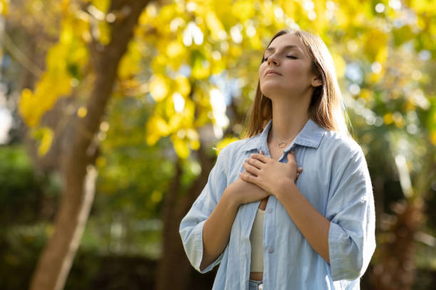 istock Woman with closed eyes putting hands on her chest 2098784034