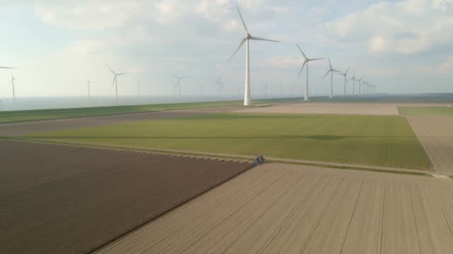 Aerial view of windturbines and tractor cultivating land, Flevoland, Netherlands