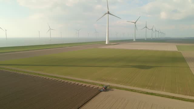 Aerial view of wind turbines and tractor plowing land, Flevoland, Netherlands