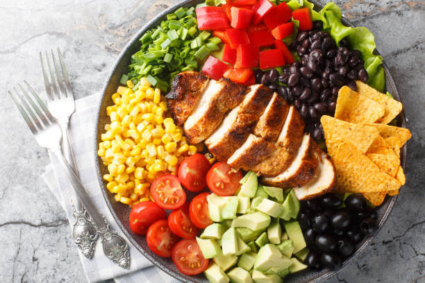 istock Tex-Mex Santa Fe chicken salad with lettuce, tomatoes, corn, black beans, pepper, avocado, olive closeup on the plate. Horizontal top view 2098840055