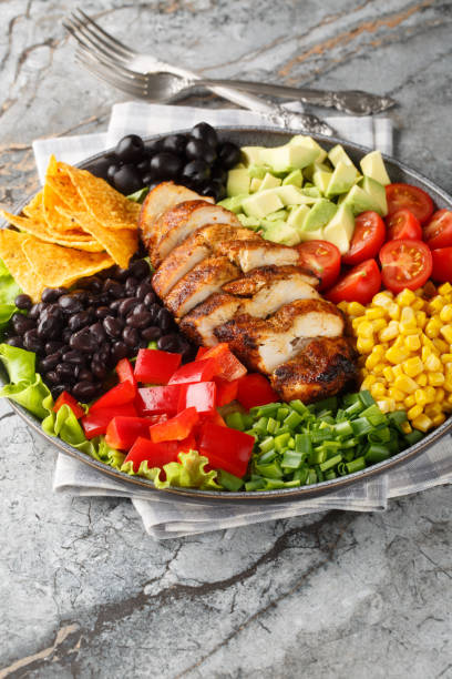 istock Santa Fe salad combines lettuce, tomatoes, corn, black beans, pepper, avocado, olive and chicken closeup on the plate. Vertical 2098841599