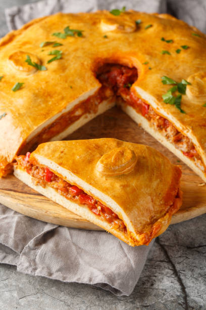istock Empanada Gallega large two-crusted savory pie from Galicia filled with meat, red peppers, tomato and lots of onion closeup on the board. Vertical 2098843174