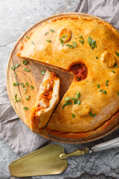 istock Empanada Gallega large two-crusted savory pie from Galicia filled with meat, red peppers, tomato and lots of onion closeup on the board. Vertical top view 2098844723