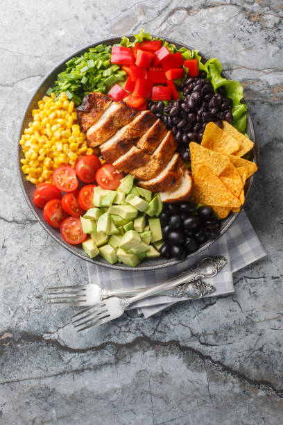 istock Santa Fe salad combines lettuce, tomatoes, corn, black beans, pepper, avocado, olive and chicken closeup on the plate. Vertical top view 2098847334