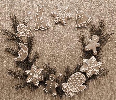 Sepia-Toned Christmas Background. Delicately Iced Gingerbread Cookies Adorned with Fir Branches on a Glittery Surface