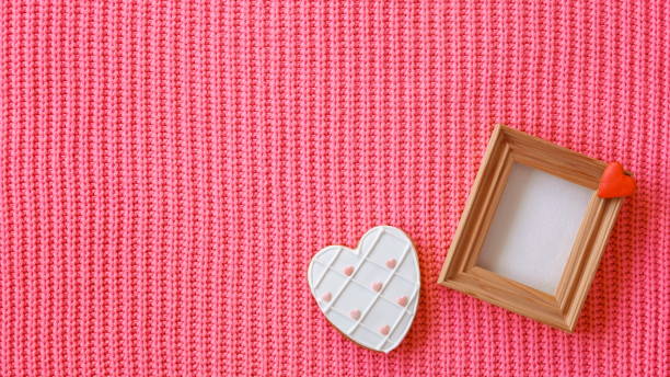 istock White Heart Shaped Gingerbread Cookie on a Woolen Red Background and Wooden Empty Frame. Valentine Mothers Day Concept. Love Background. Vintage Photo 2098872993