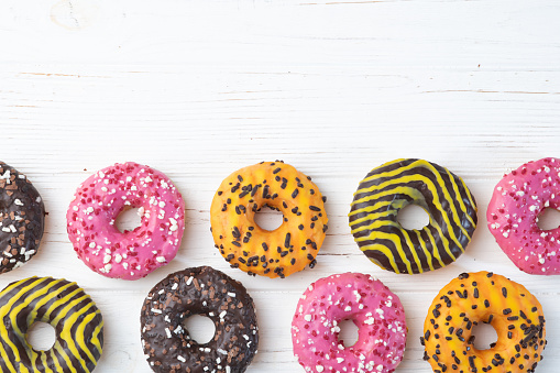 Set of colorful donuts on wooden background . Chocolate , lemon, orange and raspberry . Top view