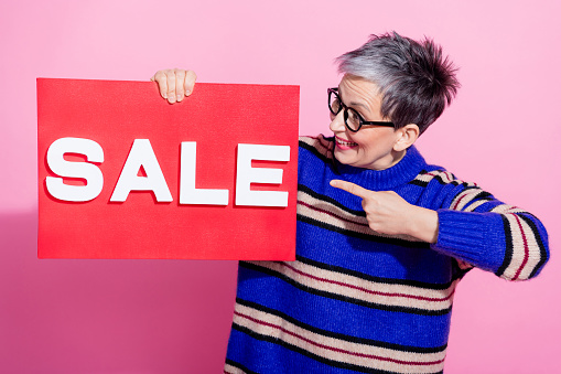 Photo portrait of pretty retired female hold point look sale plate wear trendy blue striped outfit isolated on pink color background.