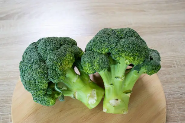 Fresh raw broccoli vegetables on wooden tray with wood texture background.