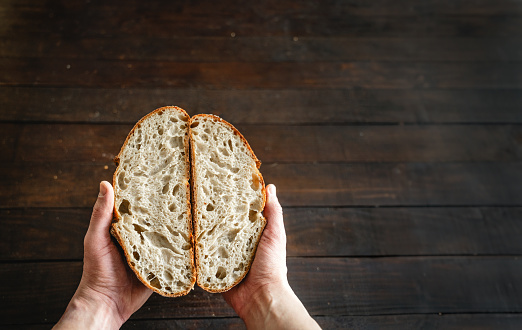 Hands holding open crumb artisan sourdough bread cut in half