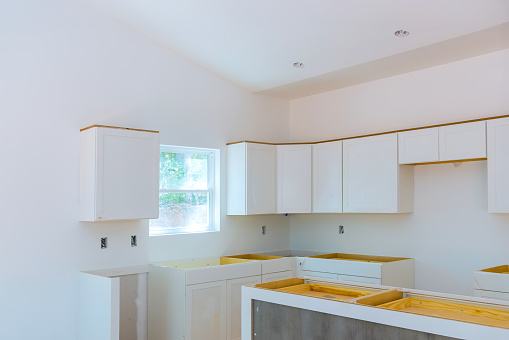 Kitchen cabinets made of wood white are being installed in newly constructed house