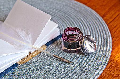 Capture the essence of traditional writing with this elegant setup featuring a stack of blank paper, a delicate quill, and a gleaming inkwell. Perfect for evoking nostalgia and creativity. Location: Fort Wayne, Indiana.