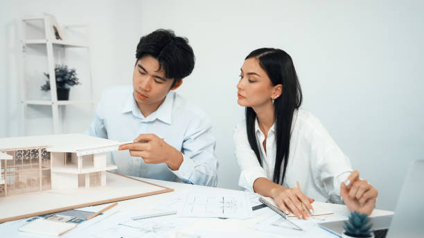istock Closeup of engineer measure house model while coworker use laptop. Immaculate. 2099046701