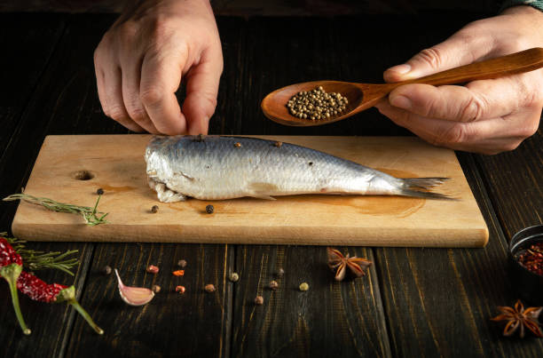 istock The chef is preparing Baltic herring fish on the kitchen table with spices and coriander for a delicious lunch. Working environment on the kitchen table 2099051971