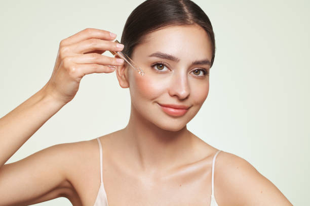 Young beautiful woman applying face serum