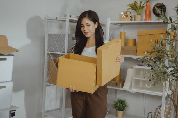 istock A young woman is putting things into boxes to pack. 2099071126