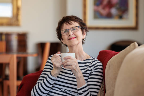 istock Smiling senior woman relaxing at home on a sofa with a coffee 2099079612